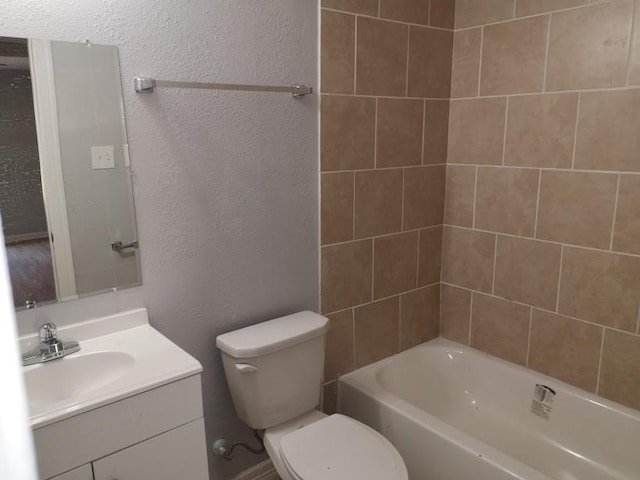 full bathroom featuring toilet, a textured wall, and vanity
