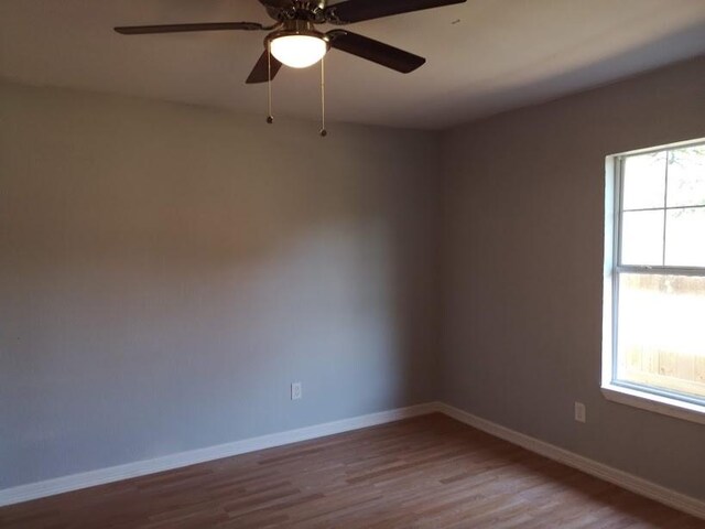 empty room featuring baseboards, ceiling fan, and wood finished floors