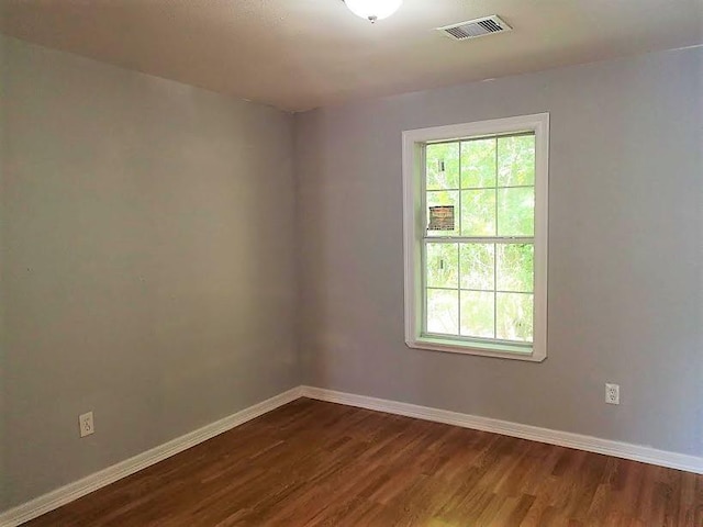 unfurnished room featuring dark wood-style flooring, baseboards, and visible vents