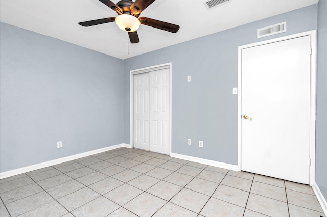 unfurnished bedroom with a closet, light tile patterned floors, and ceiling fan