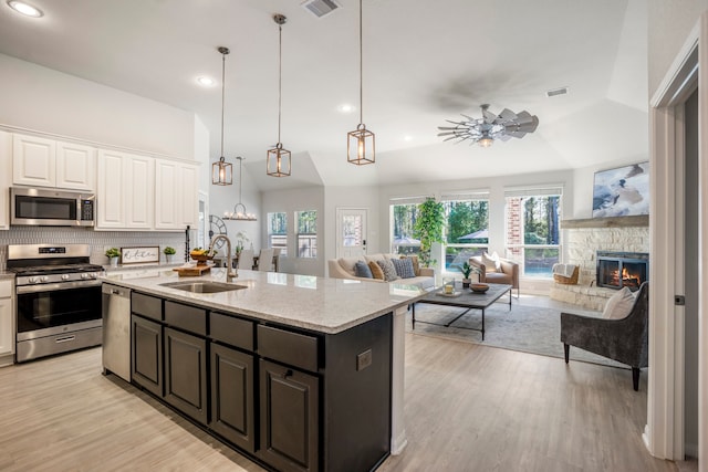 kitchen featuring appliances with stainless steel finishes, sink, lofted ceiling, and white cabinetry