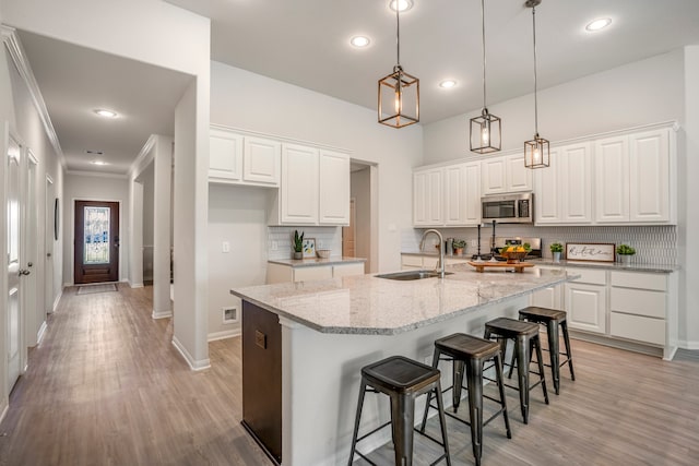 kitchen with light stone counters, white cabinetry, sink, and stainless steel appliances