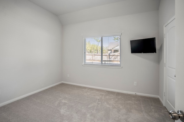 carpeted empty room with lofted ceiling