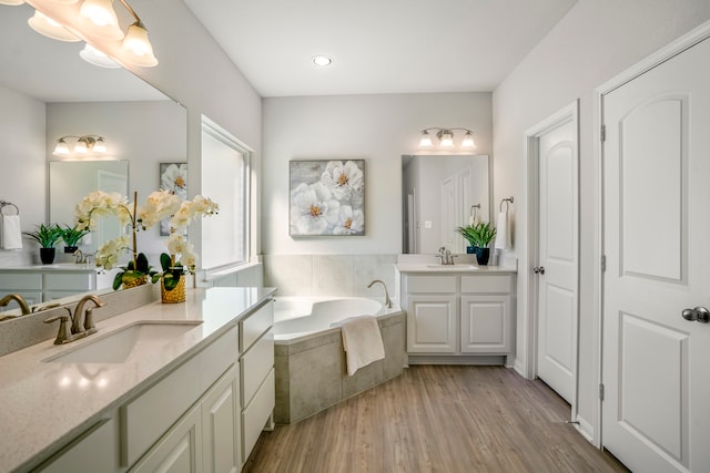 bathroom featuring tiled tub, hardwood / wood-style flooring, and vanity