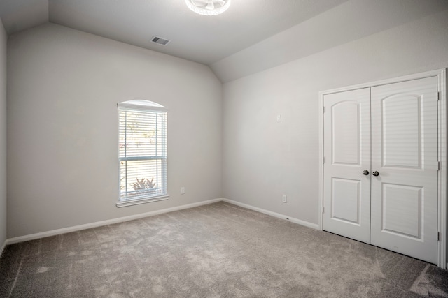 unfurnished room featuring lofted ceiling and carpet flooring