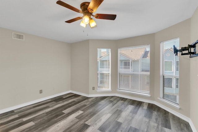 empty room featuring dark hardwood / wood-style flooring, ceiling fan, and plenty of natural light