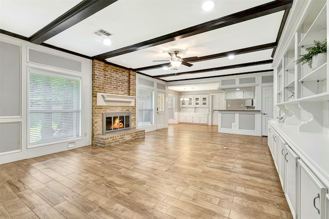 unfurnished living room featuring a brick fireplace, crown molding, ceiling fan, and light hardwood / wood-style flooring