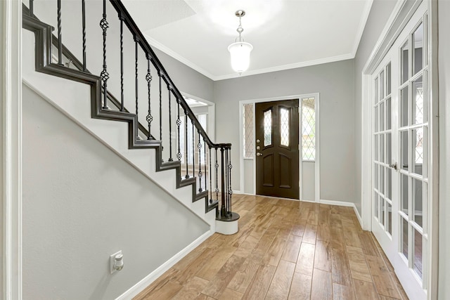 entrance foyer featuring ornamental molding, light wood-type flooring, and french doors