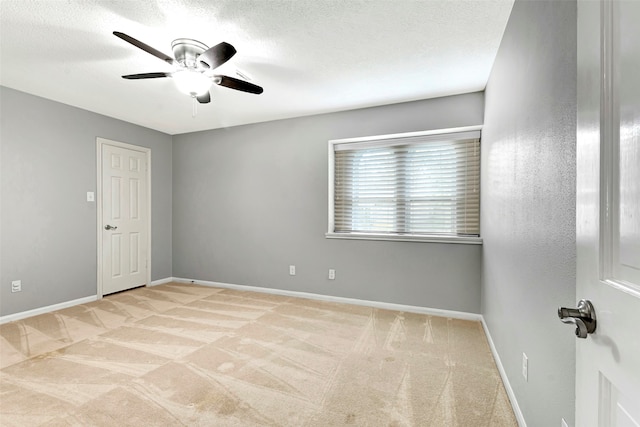 empty room featuring light carpet, ceiling fan, and a textured ceiling