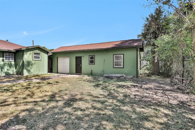 rear view of house featuring a lawn and a garage