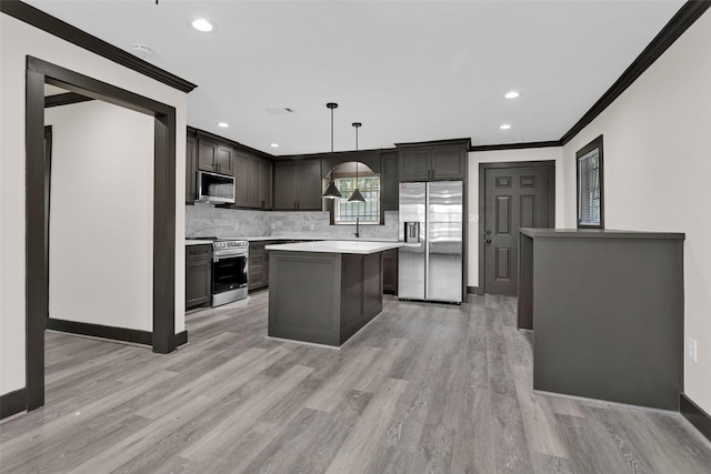 kitchen featuring appliances with stainless steel finishes, light countertops, backsplash, ornamental molding, and a kitchen island