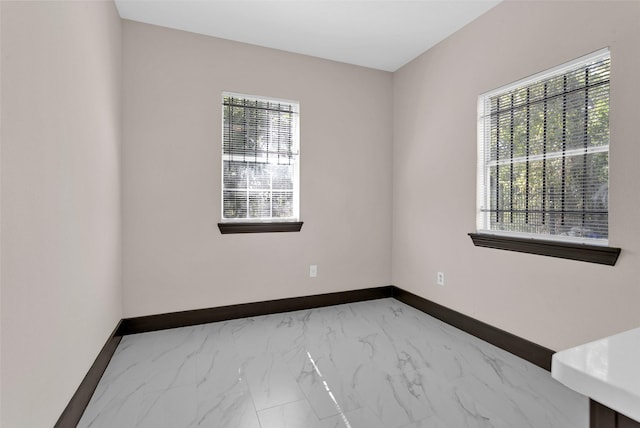 spare room featuring marble finish floor and baseboards