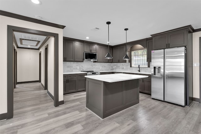 kitchen featuring pendant lighting, appliances with stainless steel finishes, light hardwood / wood-style floors, and a center island