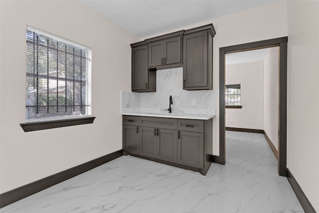 kitchen with dark brown cabinetry, sink, decorative backsplash, and a healthy amount of sunlight