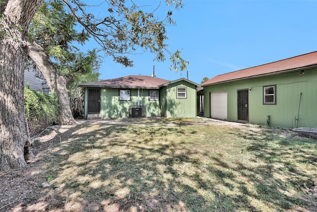 back of property with central AC unit and a yard