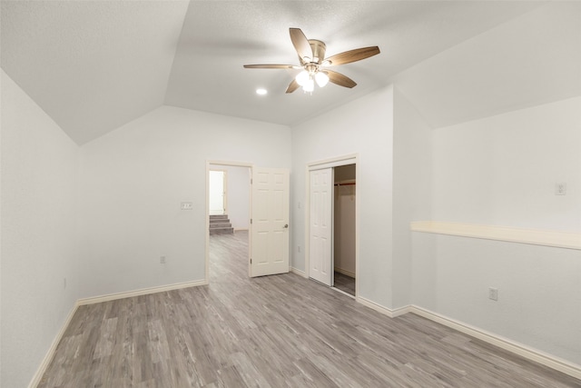 unfurnished bedroom featuring ceiling fan, lofted ceiling, a closet, and light hardwood / wood-style flooring