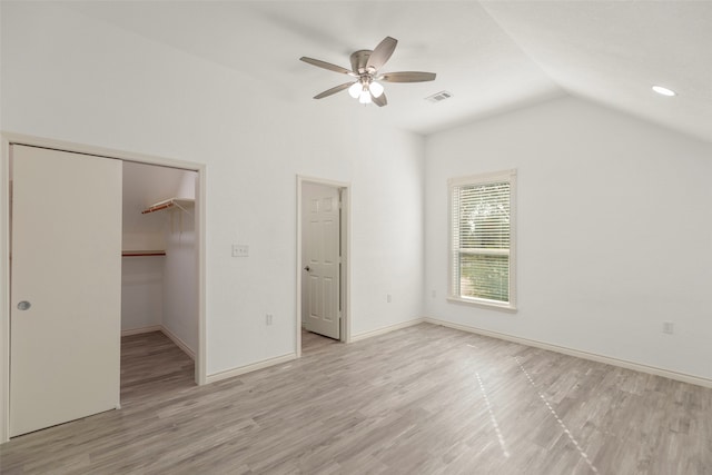 unfurnished bedroom featuring ceiling fan, light hardwood / wood-style flooring, a spacious closet, a closet, and vaulted ceiling