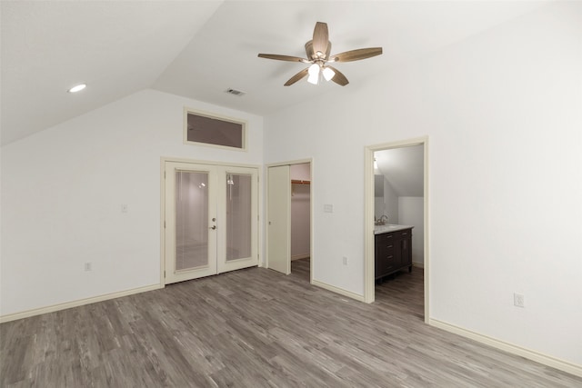 unfurnished bedroom featuring ensuite bathroom, ceiling fan, vaulted ceiling, and light hardwood / wood-style floors