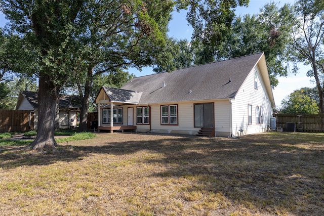 back of house with central AC unit and a lawn