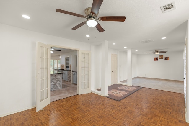 empty room with french doors, a textured ceiling, and dark tile patterned flooring