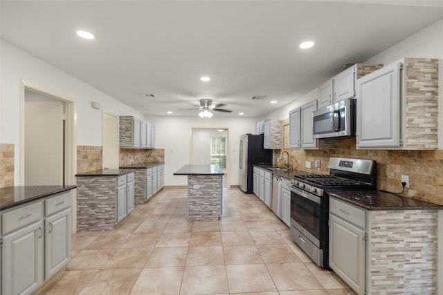 kitchen with ceiling fan, decorative backsplash, sink, appliances with stainless steel finishes, and light tile patterned floors