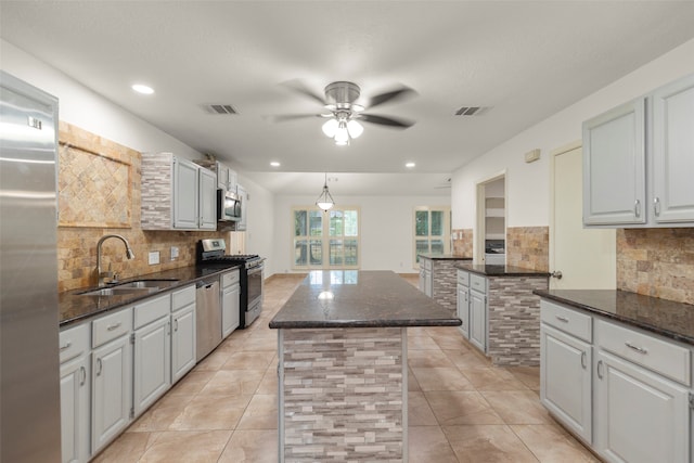 kitchen with ceiling fan, a kitchen island, sink, stainless steel appliances, and backsplash