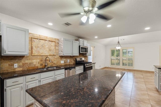 kitchen with stainless steel appliances, backsplash, sink, and a center island