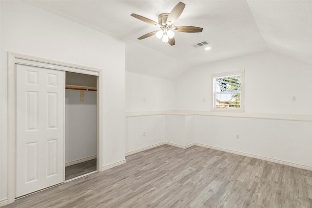 unfurnished bedroom with lofted ceiling, ceiling fan, a closet, and light wood-type flooring