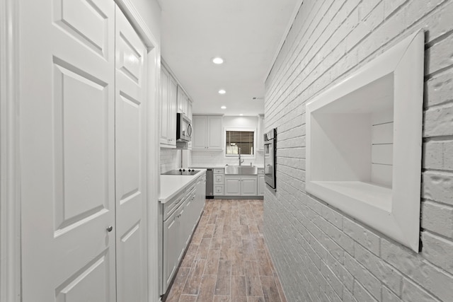 kitchen with sink, a barn door, gray cabinets, appliances with stainless steel finishes, and light hardwood / wood-style floors