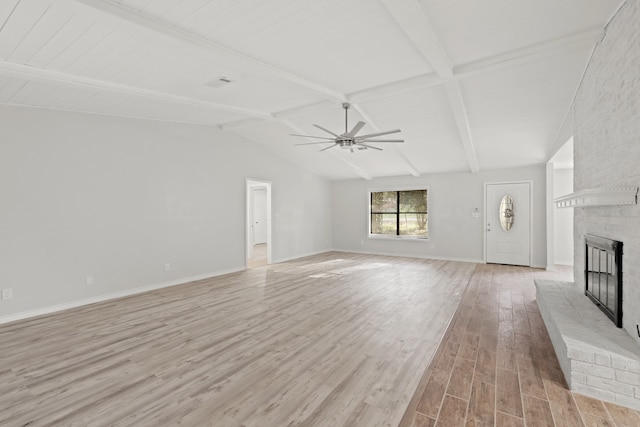 unfurnished living room with vaulted ceiling with beams, a fireplace, light wood-type flooring, and ceiling fan