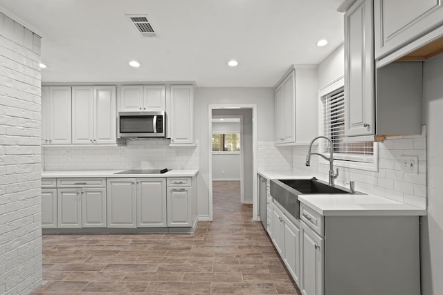 kitchen with gray cabinetry, tasteful backsplash, sink, and black electric stovetop