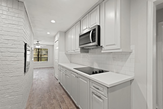 kitchen featuring appliances with stainless steel finishes, ceiling fan, wood-type flooring, and tasteful backsplash