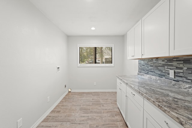 washroom with hookup for a washing machine, light wood-type flooring, and cabinets