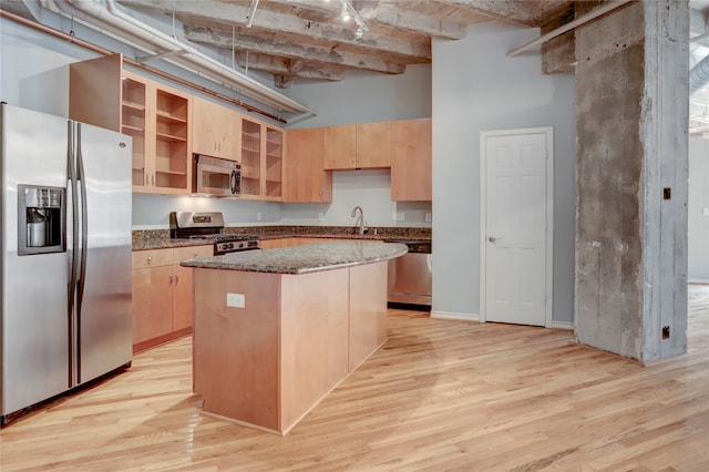 kitchen with stone countertops, a center island, light hardwood / wood-style floors, and stainless steel appliances