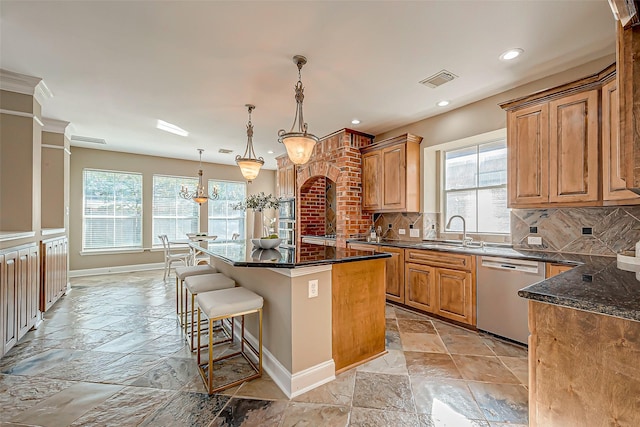 kitchen with dishwasher, backsplash, sink, hanging light fixtures, and a kitchen island