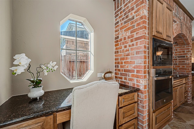 kitchen with black microwave, oven, and dark stone counters