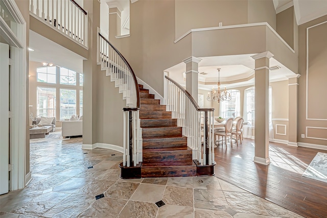 foyer with crown molding, a high ceiling, and an inviting chandelier