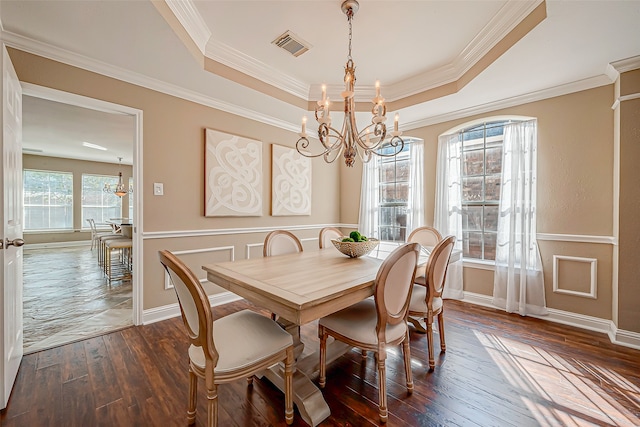 dining space with a raised ceiling, dark hardwood / wood-style flooring, a chandelier, and ornamental molding