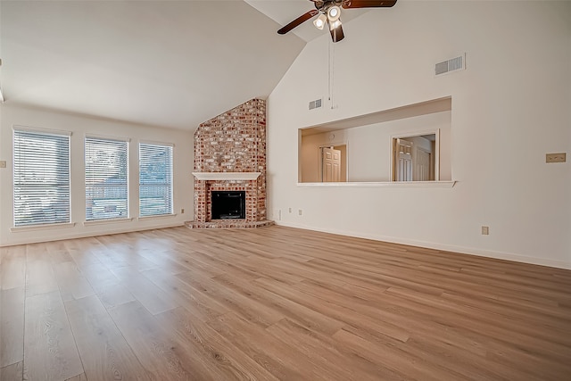 unfurnished living room with a brick fireplace, light wood-type flooring, high vaulted ceiling, and ceiling fan