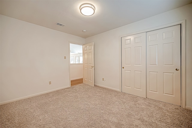 unfurnished bedroom featuring light carpet and a closet