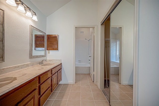 bathroom featuring tile patterned floors, vaulted ceiling, vanity, and tiled shower / bath