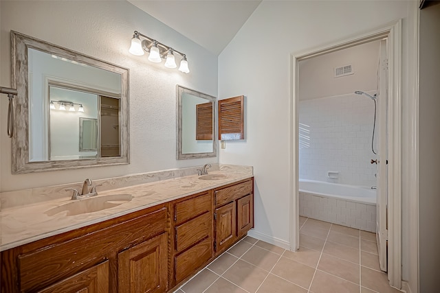 bathroom with tile patterned flooring, tiled shower / bath, vanity, and vaulted ceiling