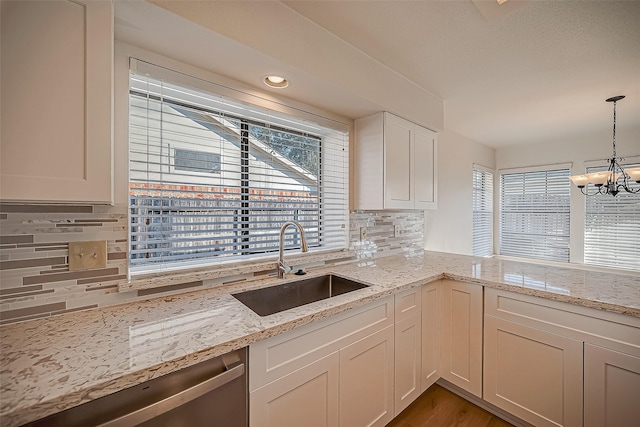 2810 Pineleaf Dr, Sugar Land, TX 77479 - kitchen with a sink, a chandelier, tasteful backsplash, light stone counters, and white cabinets