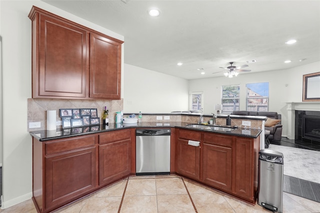 kitchen with dark stone counters, sink, decorative backsplash, kitchen peninsula, and stainless steel dishwasher