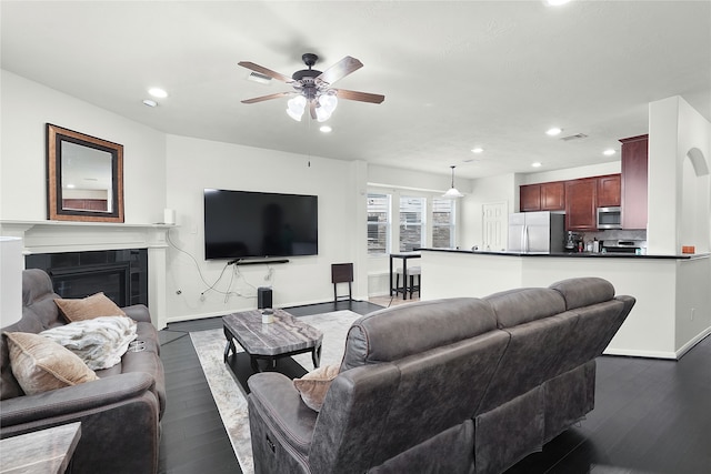 living room with ceiling fan, dark hardwood / wood-style flooring, and a tile fireplace