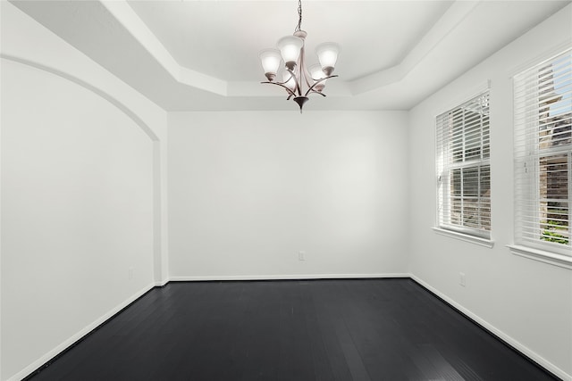 spare room with a notable chandelier, wood-type flooring, and a raised ceiling