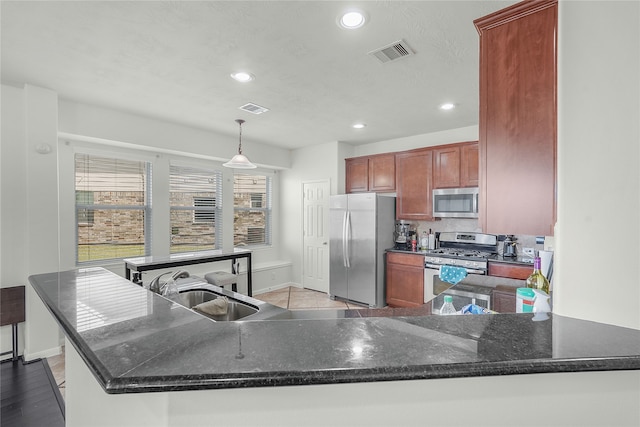 kitchen featuring pendant lighting, light hardwood / wood-style flooring, sink, kitchen peninsula, and appliances with stainless steel finishes