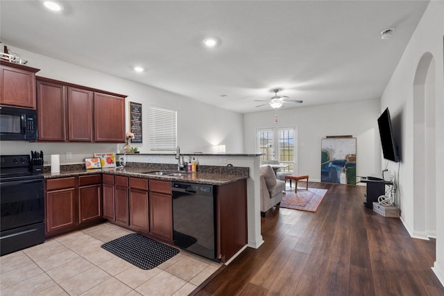 kitchen featuring dark stone countertops, sink, light hardwood / wood-style floors, and black appliances