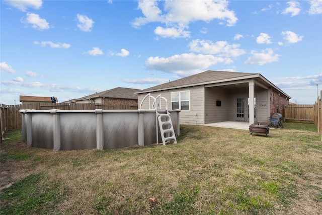 rear view of house featuring a yard, a fenced in pool, and a patio