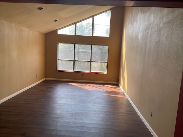 empty room featuring a healthy amount of sunlight, dark wood-type flooring, and vaulted ceiling